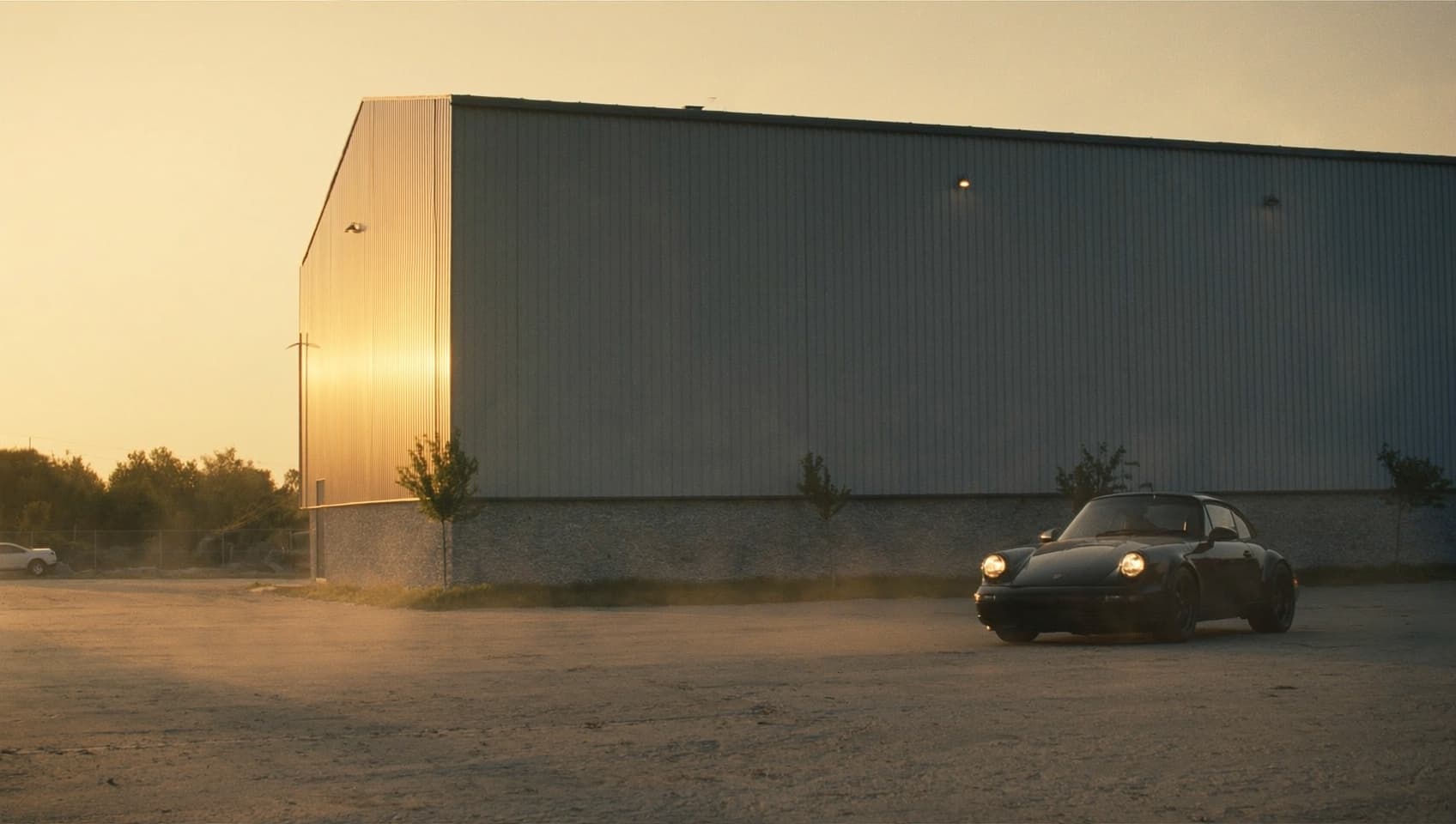 Logistics hall in evening light with a dark sports car in front